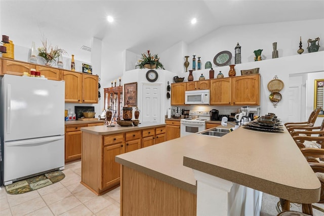 kitchen with light tile patterned floors, white appliances, a spacious island, and a breakfast bar