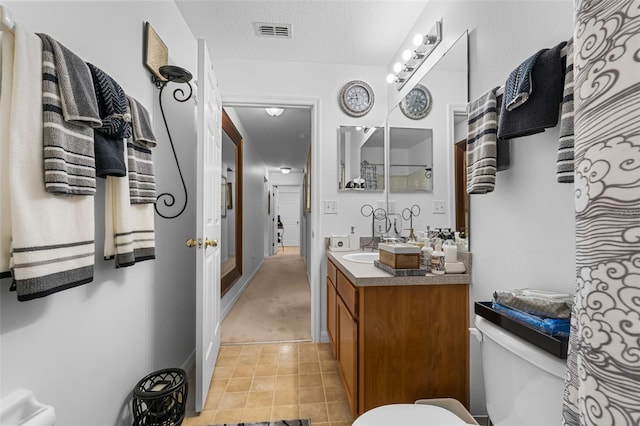 bathroom featuring vanity, toilet, and a textured ceiling