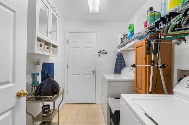 laundry area featuring a textured ceiling, cabinets, and separate washer and dryer