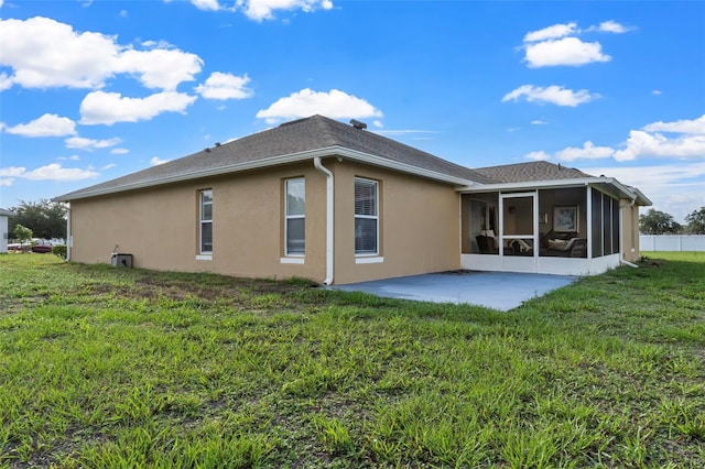 rear view of house with a sunroom, a patio area, and a lawn