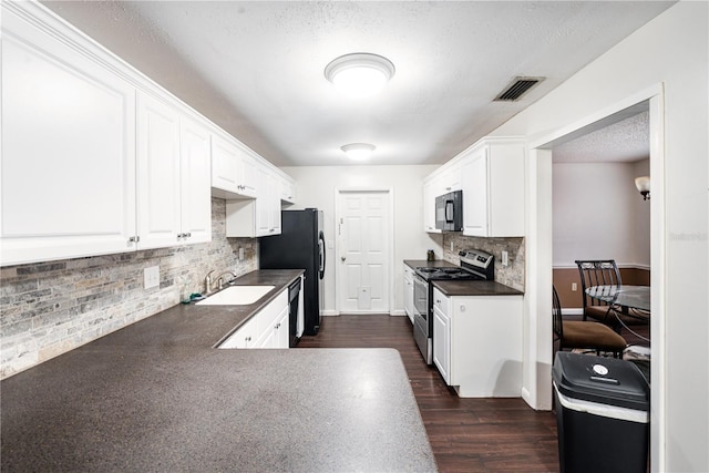 kitchen with white cabinetry, a sink, dark countertops, visible vents, and black appliances