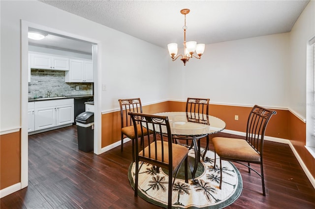 dining room with dark wood finished floors, baseboards, a textured ceiling, and a chandelier