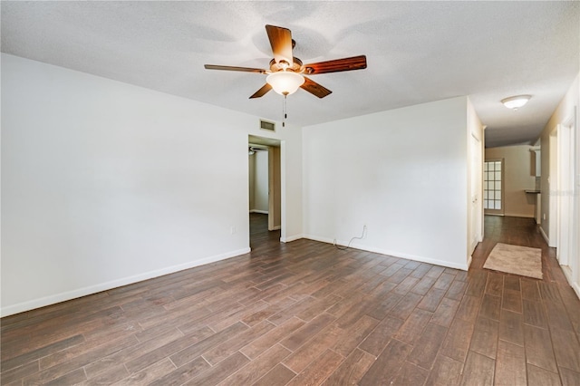 spare room featuring a ceiling fan, dark wood-style floors, baseboards, and visible vents