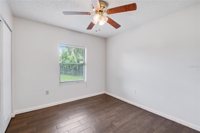 spare room featuring a textured ceiling, baseboards, ceiling fan, and dark wood finished floors