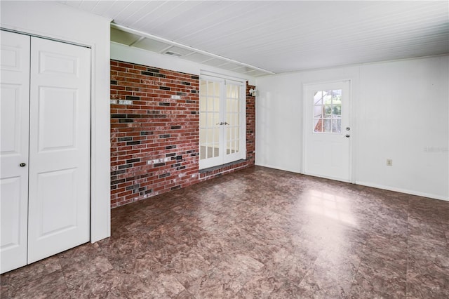 spare room with tile patterned floors, french doors, and brick wall