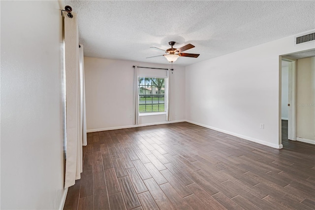 empty room featuring dark wood-type flooring, baseboards, visible vents, and a ceiling fan
