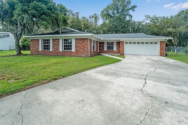 ranch-style house with concrete driveway, fence, an attached garage, brick siding, and a front lawn
