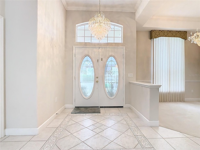 foyer entrance with crown molding, a notable chandelier, light tile patterned flooring, and baseboards