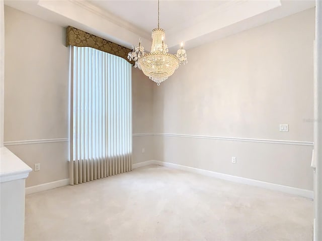 unfurnished room with a chandelier, carpet, a tray ceiling, and baseboards