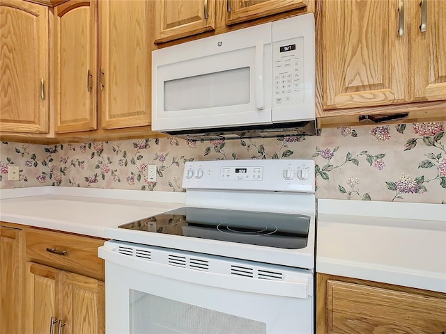 kitchen featuring wallpapered walls, white appliances, and light countertops