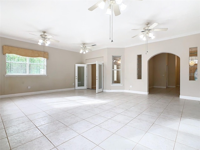 unfurnished room with light tile patterned floors, a ceiling fan, baseboards, arched walkways, and crown molding