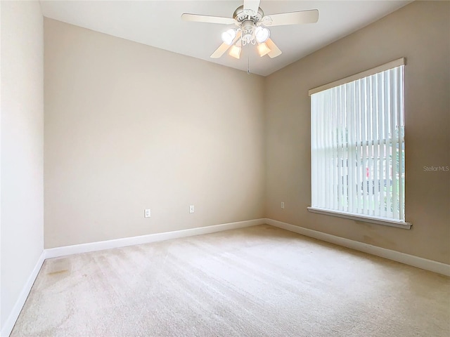 spare room featuring ceiling fan, baseboards, and light carpet