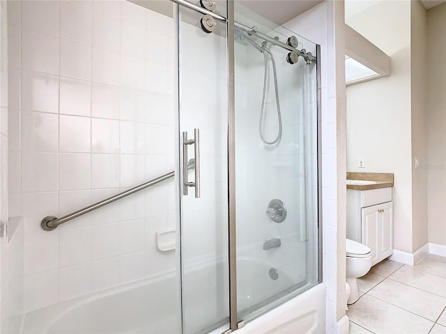 bathroom featuring tile patterned floors, toilet, combined bath / shower with glass door, baseboards, and vanity