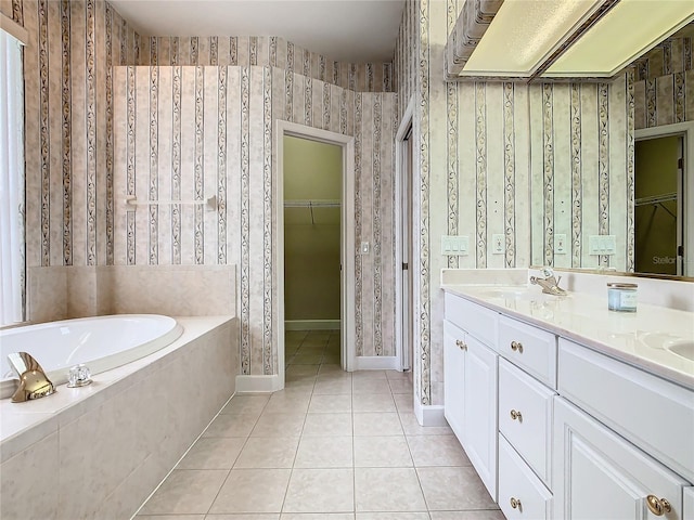 bathroom with tile patterned floors, a sink, wallpapered walls, a bath, and a spacious closet