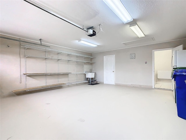 garage featuring freestanding refrigerator, a garage door opener, and a sink