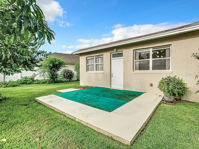 exterior space with stucco siding and a lawn