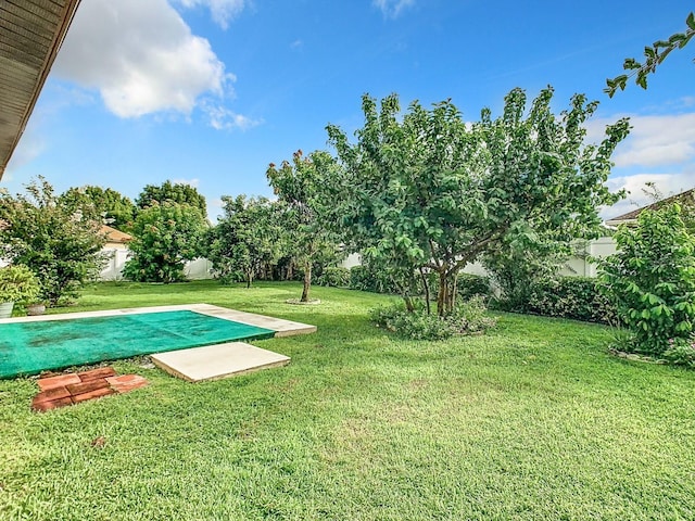 view of swimming pool with a lawn and fence