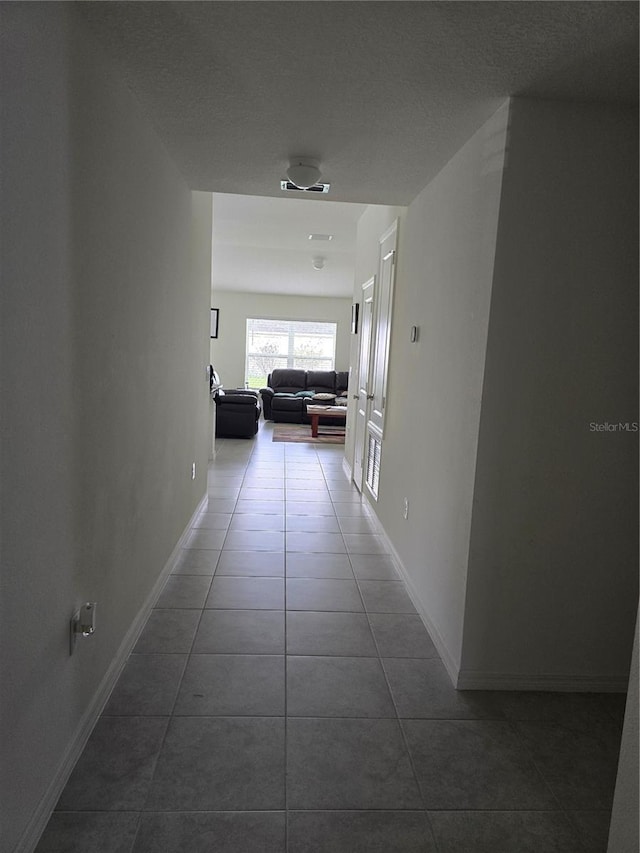 corridor featuring a textured ceiling and tile patterned floors