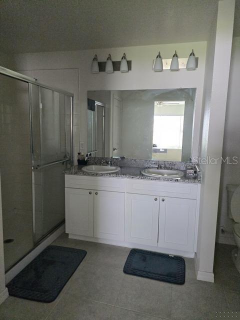 bathroom with vanity, toilet, tile patterned floors, and a shower with door