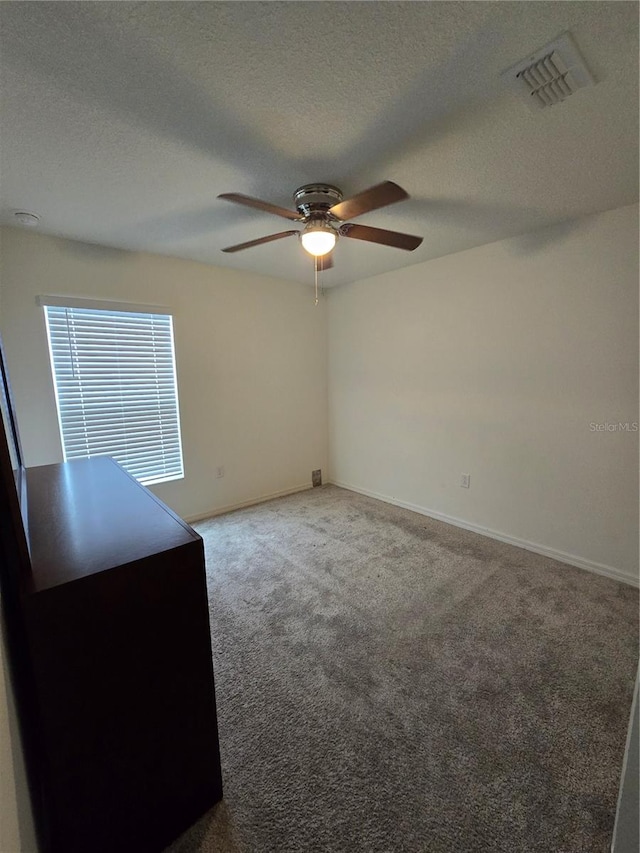 carpeted spare room with a textured ceiling and ceiling fan