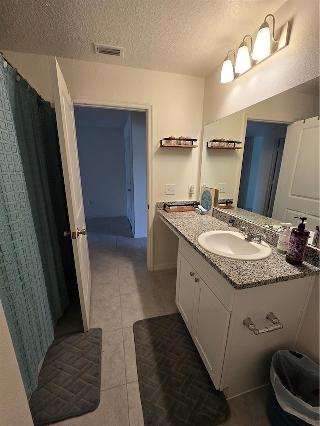 bathroom with vanity, a textured ceiling, and tile patterned floors