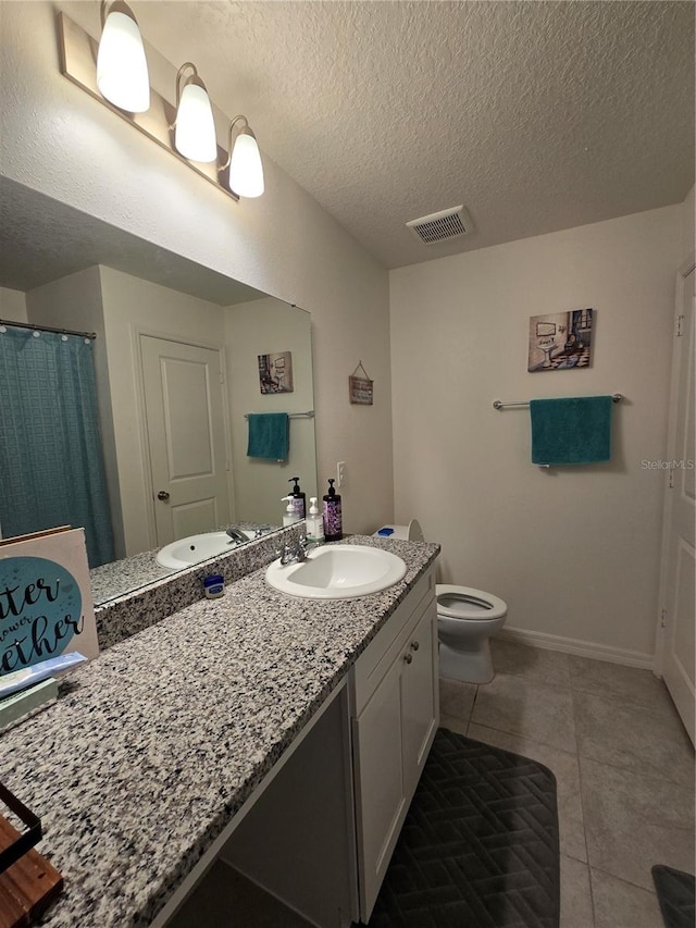 bathroom featuring tile patterned floors, toilet, a textured ceiling, and vanity