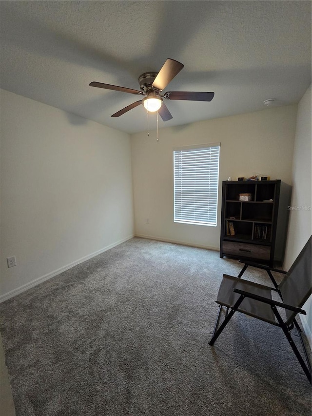 living area featuring ceiling fan, carpet, and a textured ceiling