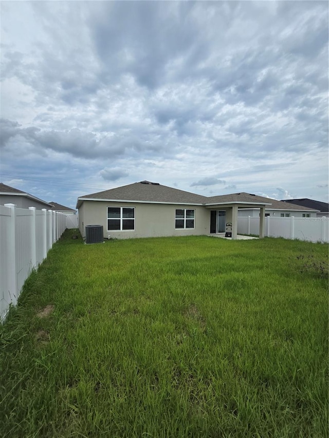 back of house with a yard and central AC unit