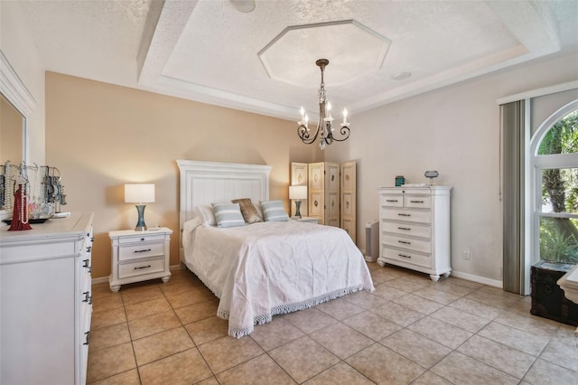 tiled bedroom with a textured ceiling, a tray ceiling, and a chandelier