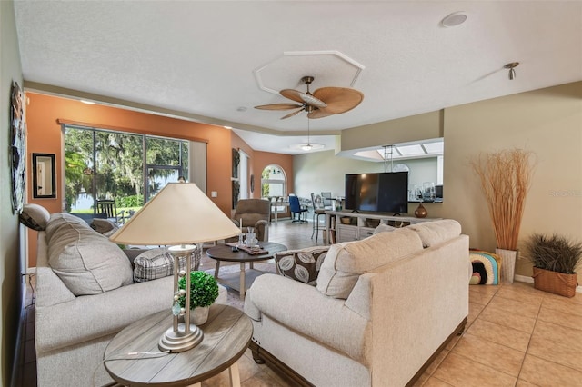 living room featuring ceiling fan, a textured ceiling, and light tile patterned floors