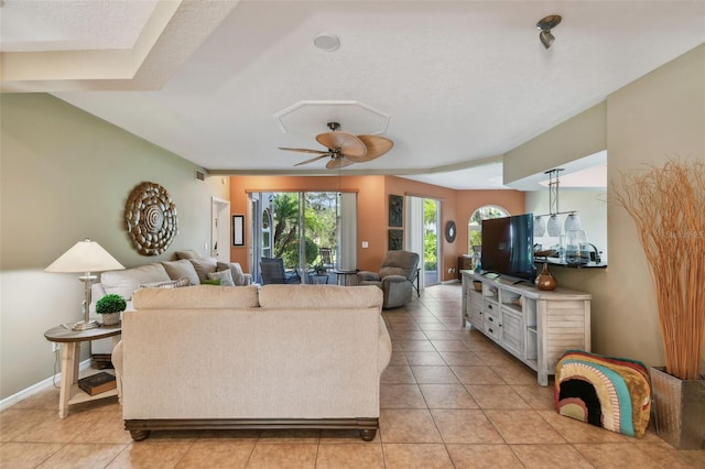 living room with ceiling fan, light tile patterned flooring, and a textured ceiling