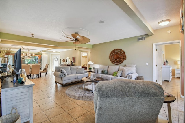 living room with ceiling fan with notable chandelier, tile patterned flooring, and a textured ceiling