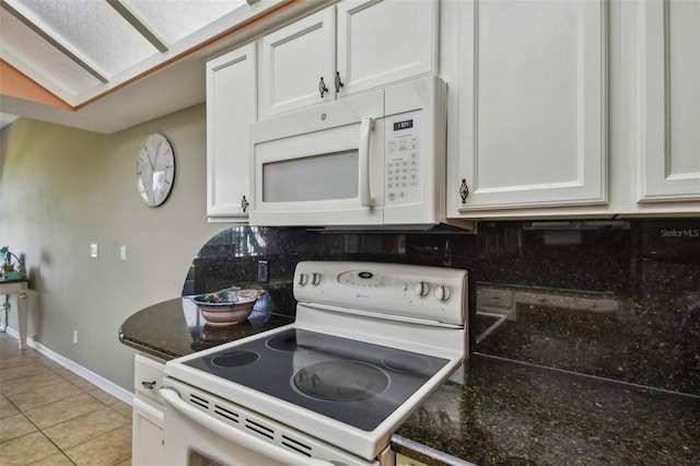 kitchen with white cabinets, light tile patterned floors, white appliances, backsplash, and dark stone counters