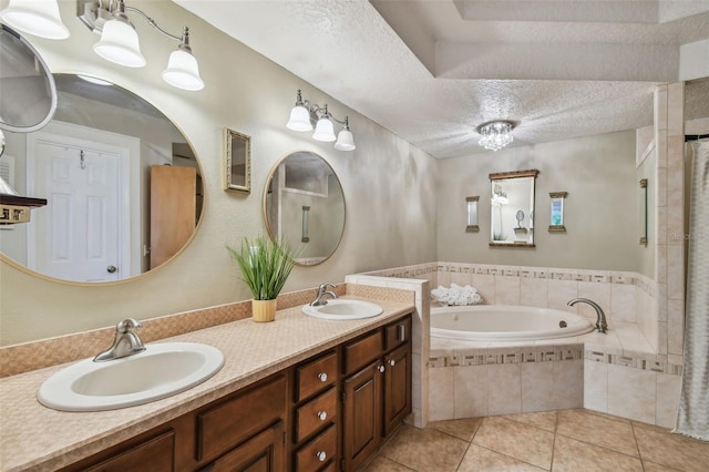 bathroom featuring tile patterned flooring, tiled tub, vanity, and a textured ceiling