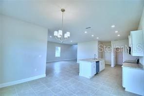 kitchen featuring a kitchen island with sink, a chandelier, decorative light fixtures, and white cabinets