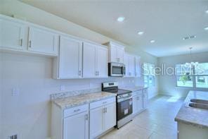 kitchen featuring light stone counters, stainless steel appliances, and white cabinetry