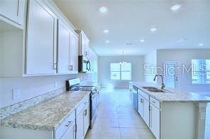 kitchen featuring appliances with stainless steel finishes, an island with sink, sink, white cabinets, and light tile patterned flooring