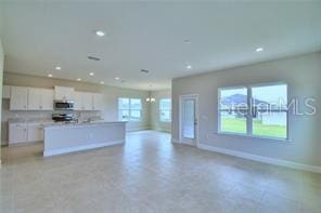 kitchen with a center island with sink, a wealth of natural light, and white cabinetry