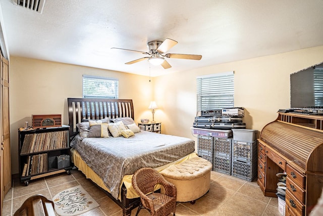 bedroom featuring a textured ceiling, light tile patterned flooring, and ceiling fan