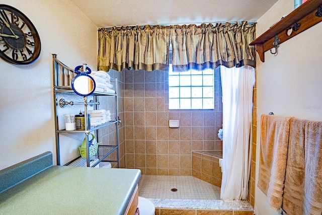 bathroom with curtained shower, tile patterned flooring, a textured ceiling, toilet, and vanity