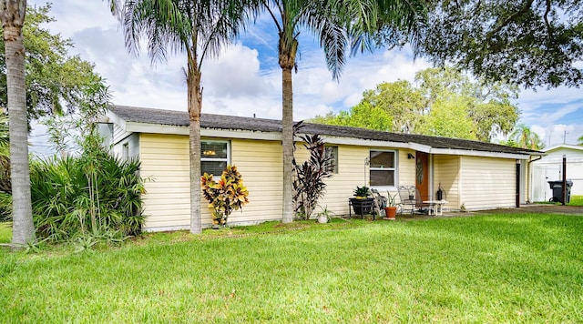 4822 Melody Ln, Lakeland, FL 33805 - back of house with an attached garage, a lawn, and driveway