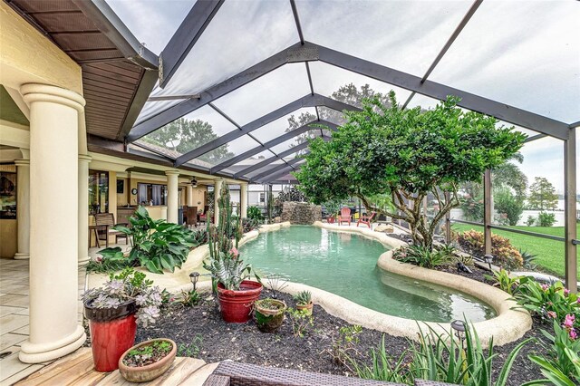 view of pool with pool water feature, a patio, and glass enclosure