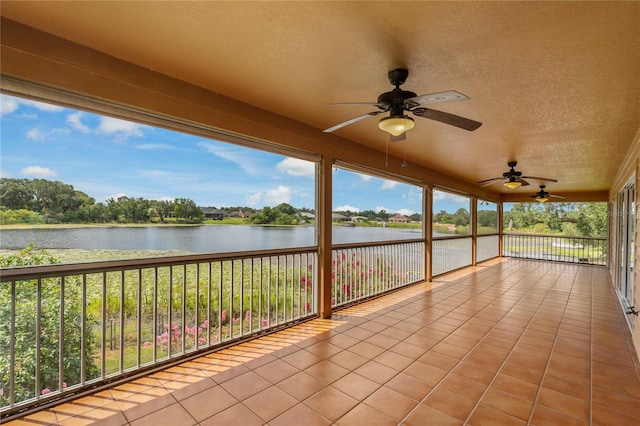 unfurnished sunroom featuring a healthy amount of sunlight, ceiling fan, and a water view