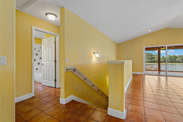 hallway featuring lofted ceiling, tile patterned floors, and a textured ceiling