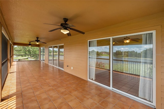 unfurnished sunroom featuring a water view and ceiling fan