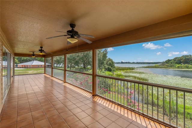 unfurnished sunroom with ceiling fan and a water view