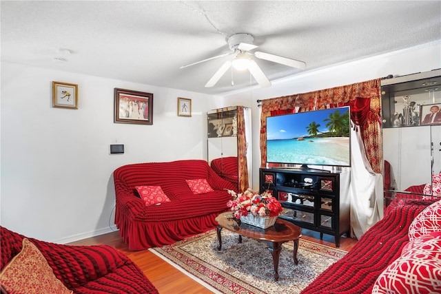 living room featuring hardwood / wood-style floors, ceiling fan, and a textured ceiling