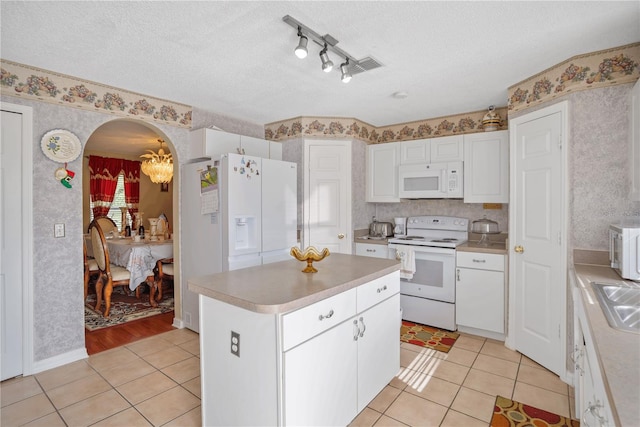 kitchen featuring a textured ceiling, white appliances, light hardwood / wood-style flooring, a center island, and white cabinetry