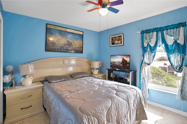 bedroom featuring ceiling fan, light tile patterned floors, and a textured ceiling