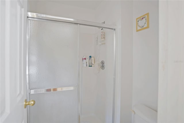 bathroom with a shower with shower door and toilet